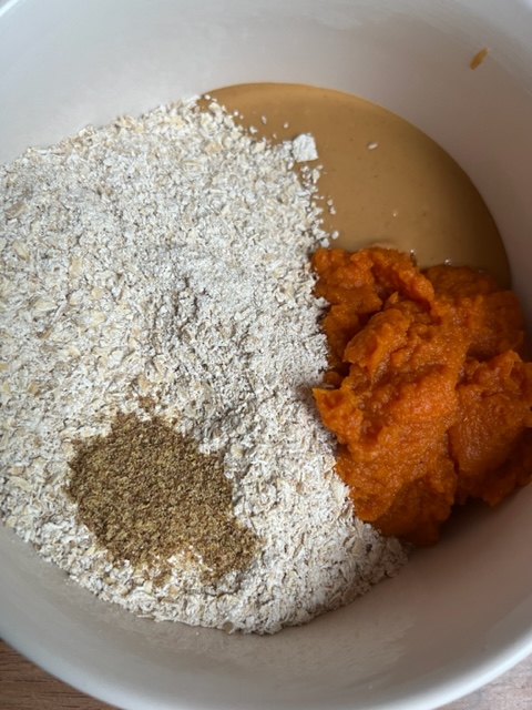 healthy ingredients for no bake pumpkin dog treats. oats, canned pumpkin, peanut butter, flax meal in dog bowl